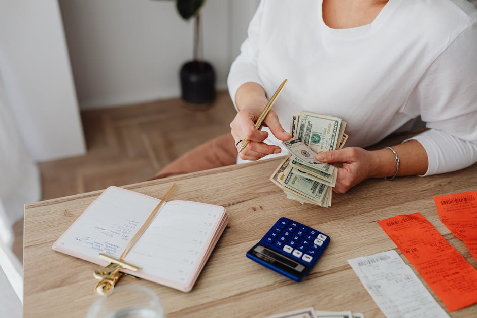 Woman sorting finances with a calculator, cash, and receipts at a desk